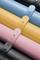 'Close-up of coloured faux leather rolls in blue, yellow, pink and black, stacked on top of each other, with attached straps and rivets.'