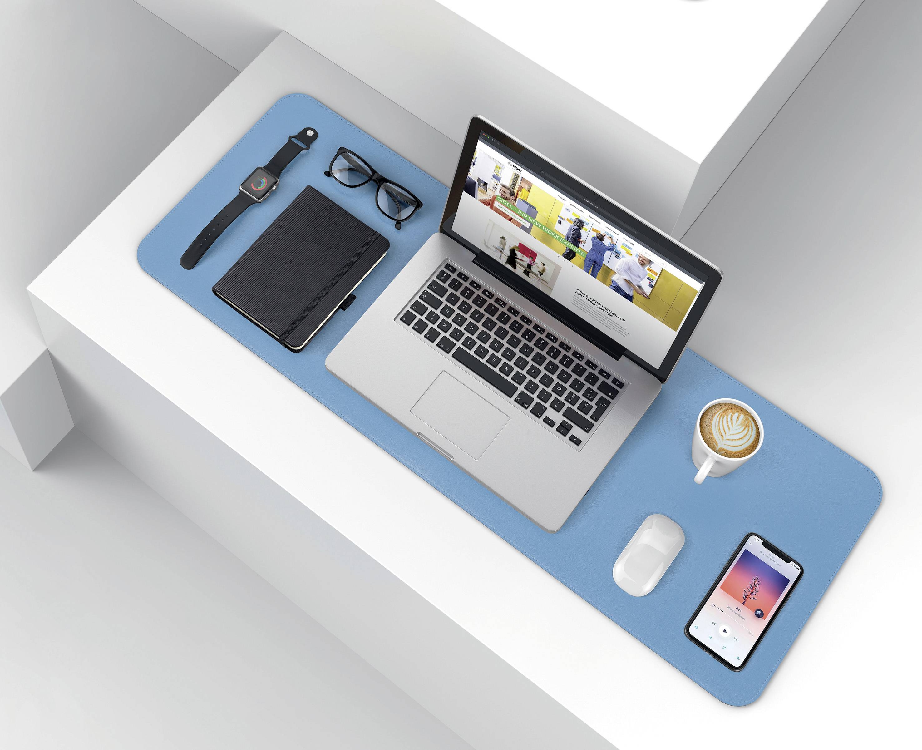 A neatly organised desk with a laptop, mobile phone, notebook, glasses, watch and a cup of cappuccino on a blue surface.