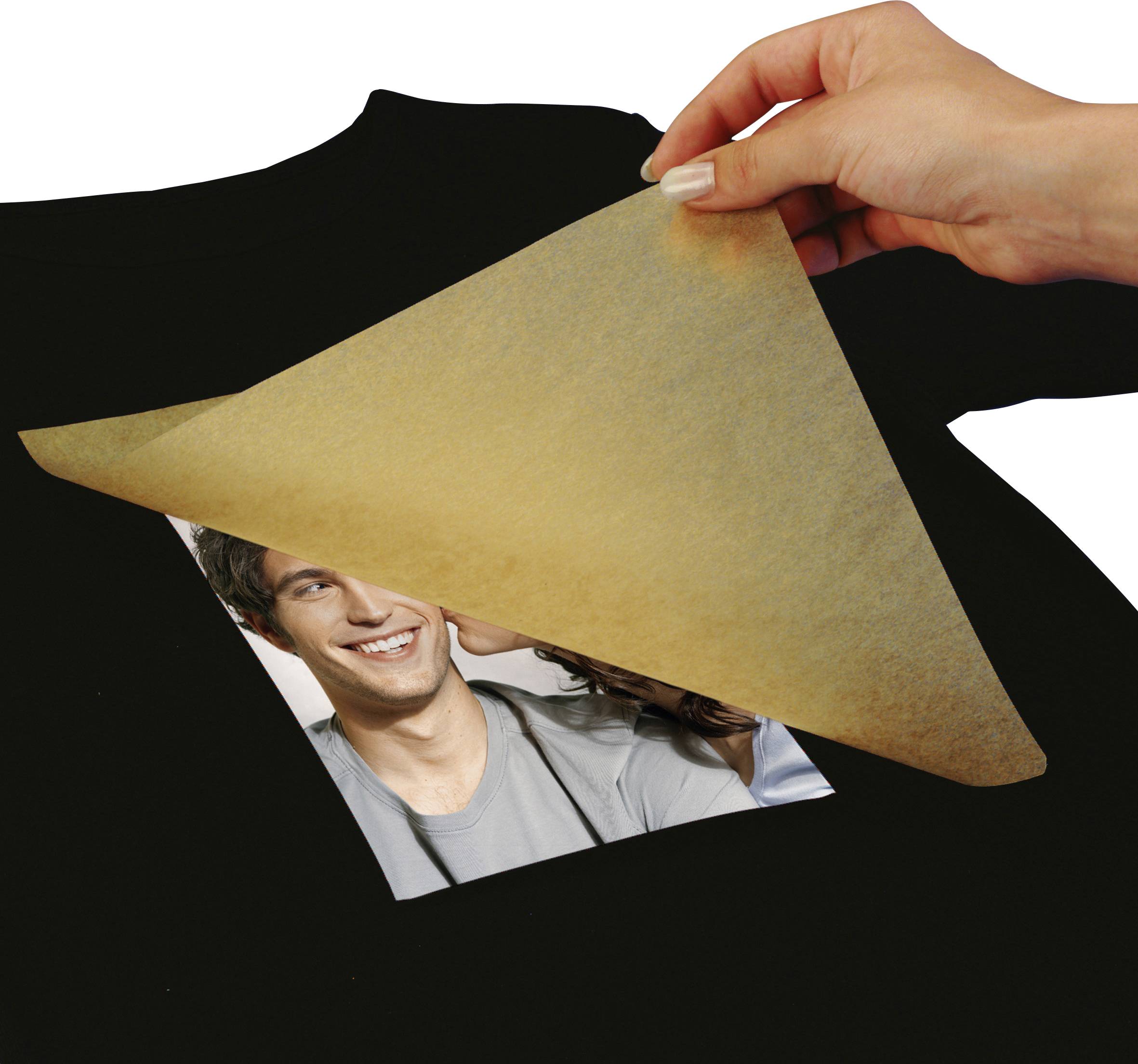 A black T-shirt is being printed with a photo and transfer paper. A hand is carefully peeling off the paper.