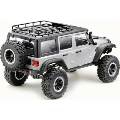 A silver remote-controlled off-road vehicle with large tyres and a roof rack, captured slightly from the rear side.