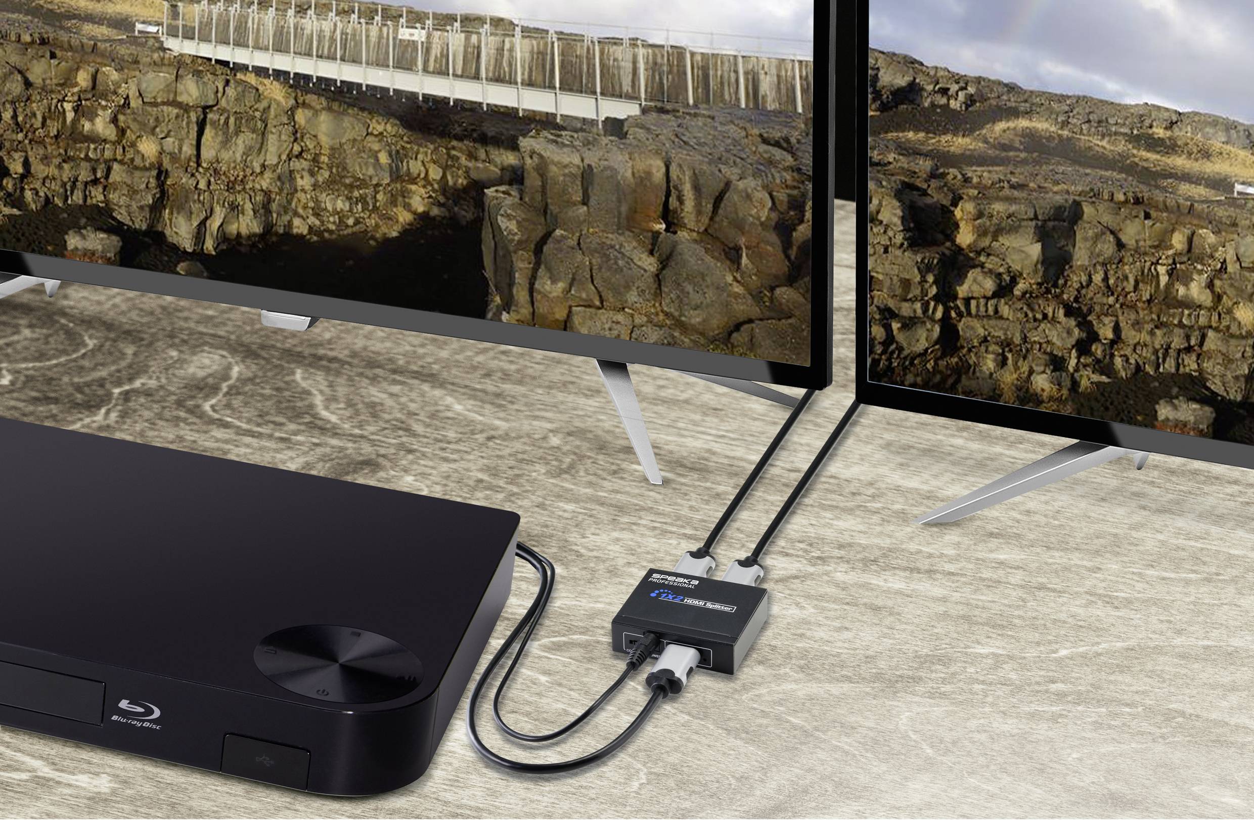 Blu-ray player connected to a splitter and two monitors displaying a rocky landscape.