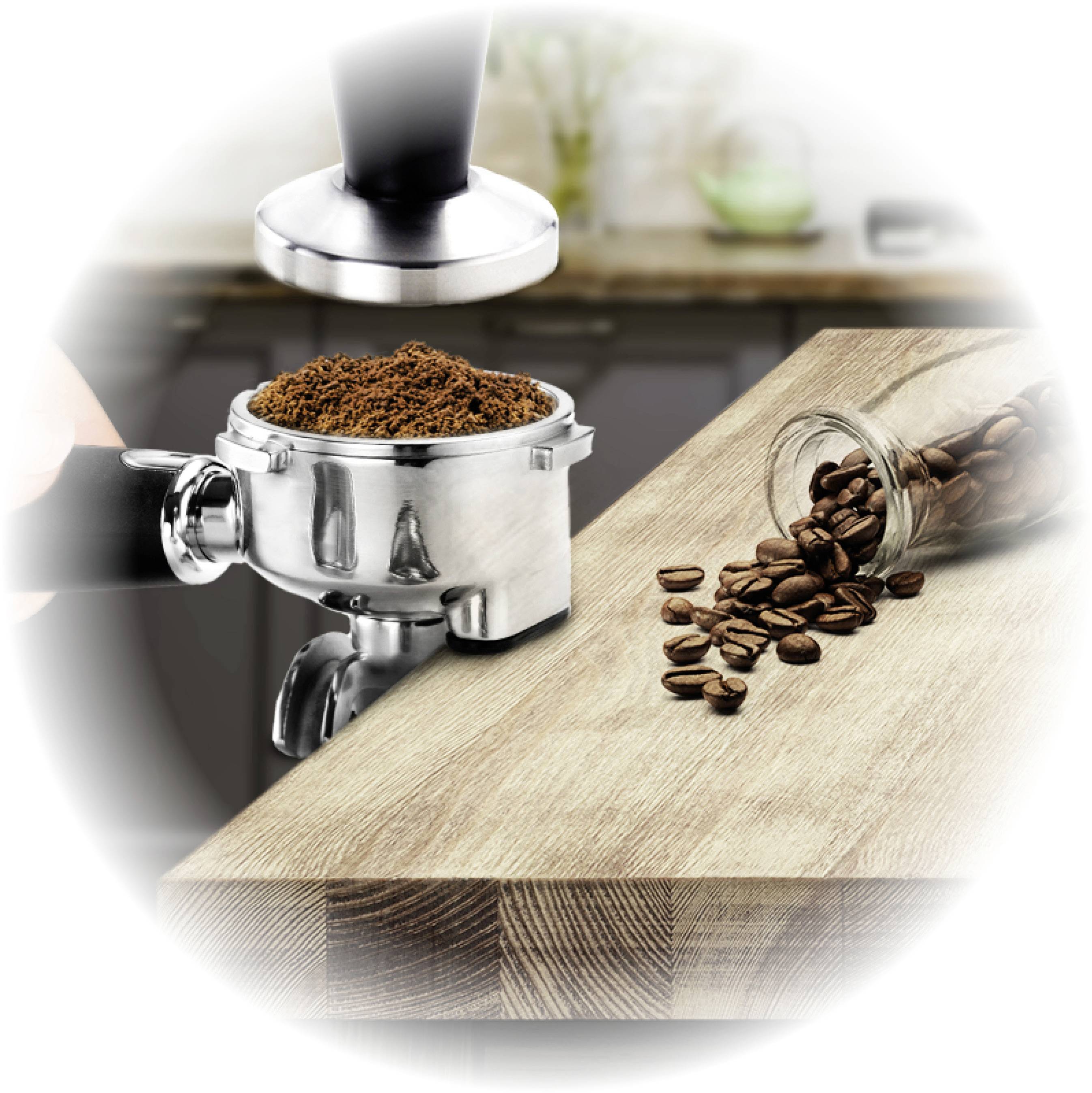 A portafilter is being filled with ground coffee and tamped, with coffee beans and a kitchen counter visible in the background.