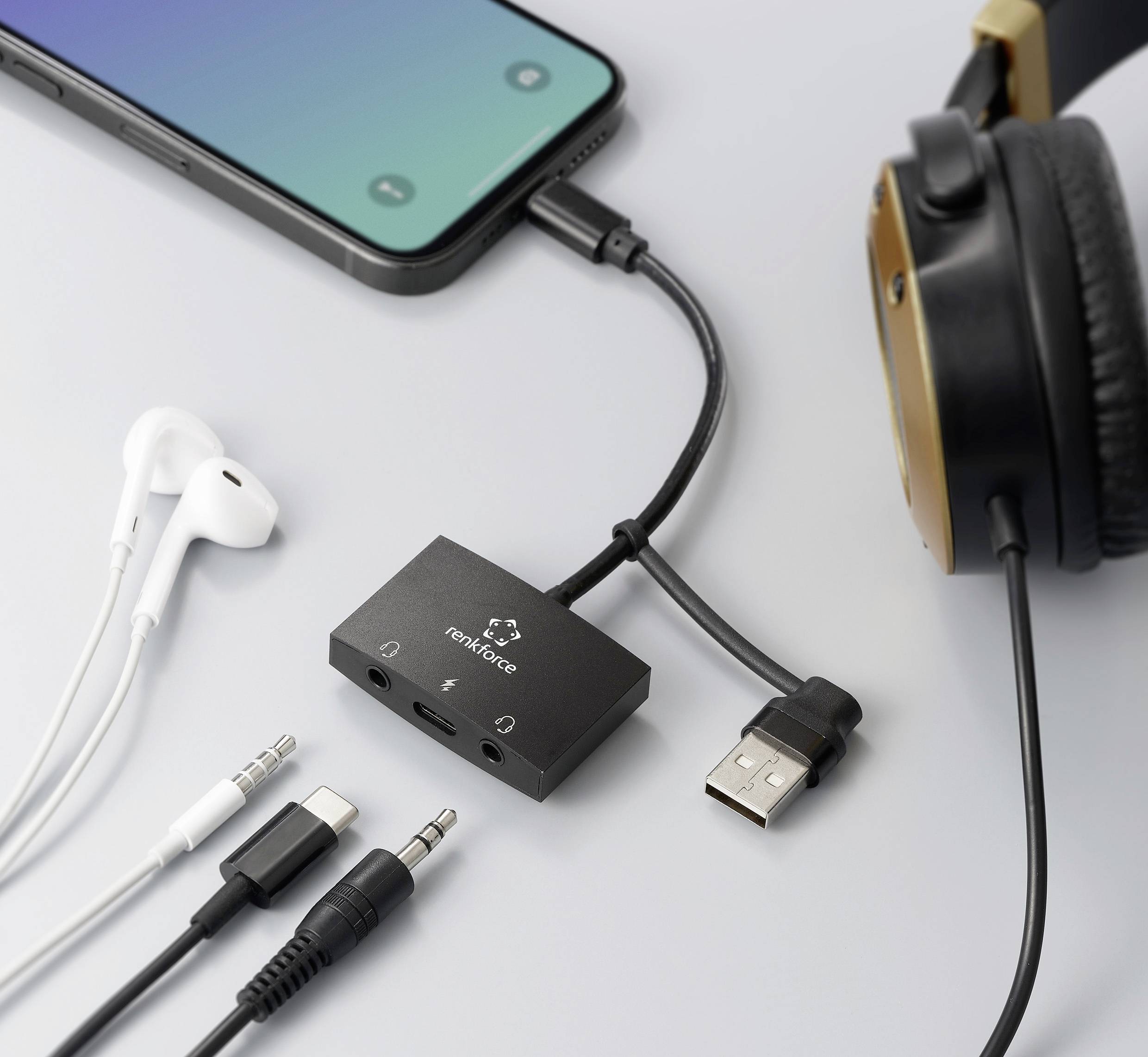 Smartphone, headphones and adapter connected. White earbuds, USB cable and audio cable beside them. Shows device connections.