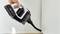 A hand operates a cordless vacuum cleaner, which is cleaning a corner between the wall and floor.