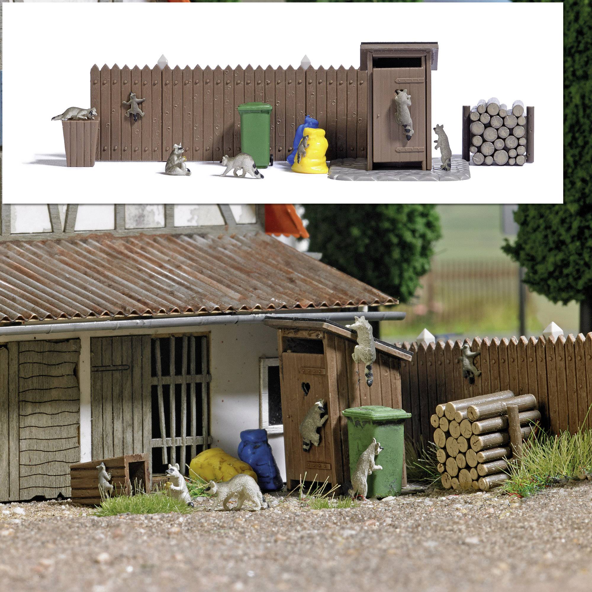 A miniature scene depicts raccoons on a farmyard. They are climbing on dustbins and a fence beside a woodpile.