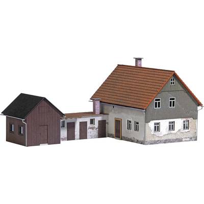 Two interconnected buildings: on the left, a smaller, dark house and on the right, a larger, two-storey house with a red roof.