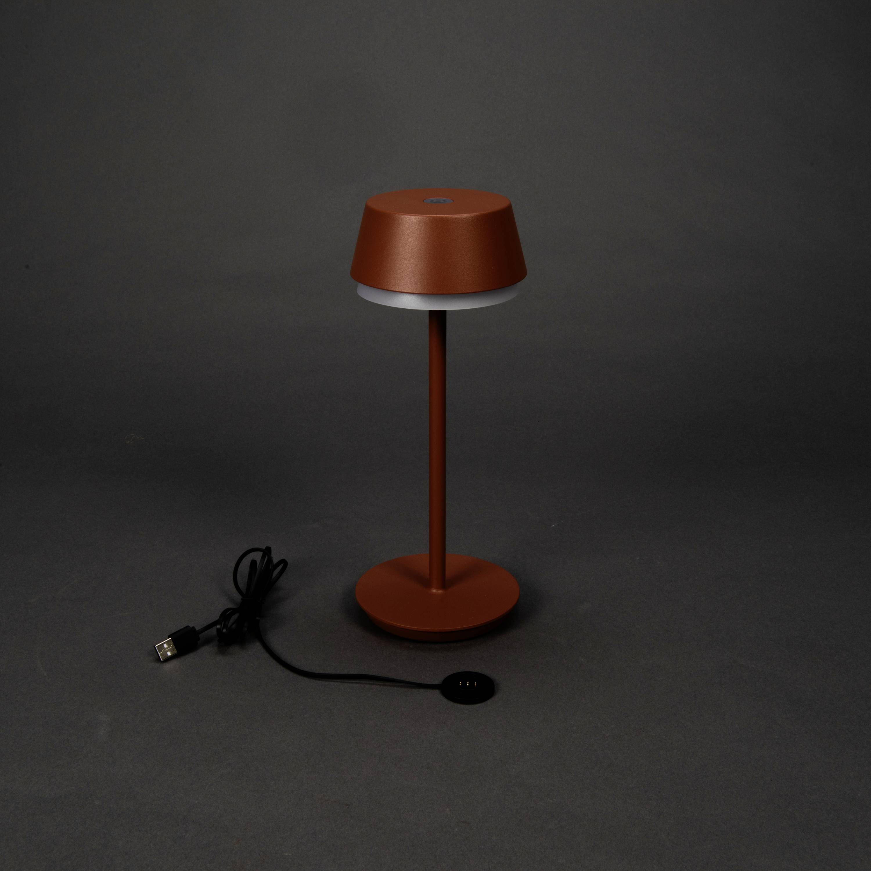 A red table lamp with a modern design, comprising a round lampshade and base, with a USB charging cable beside it.