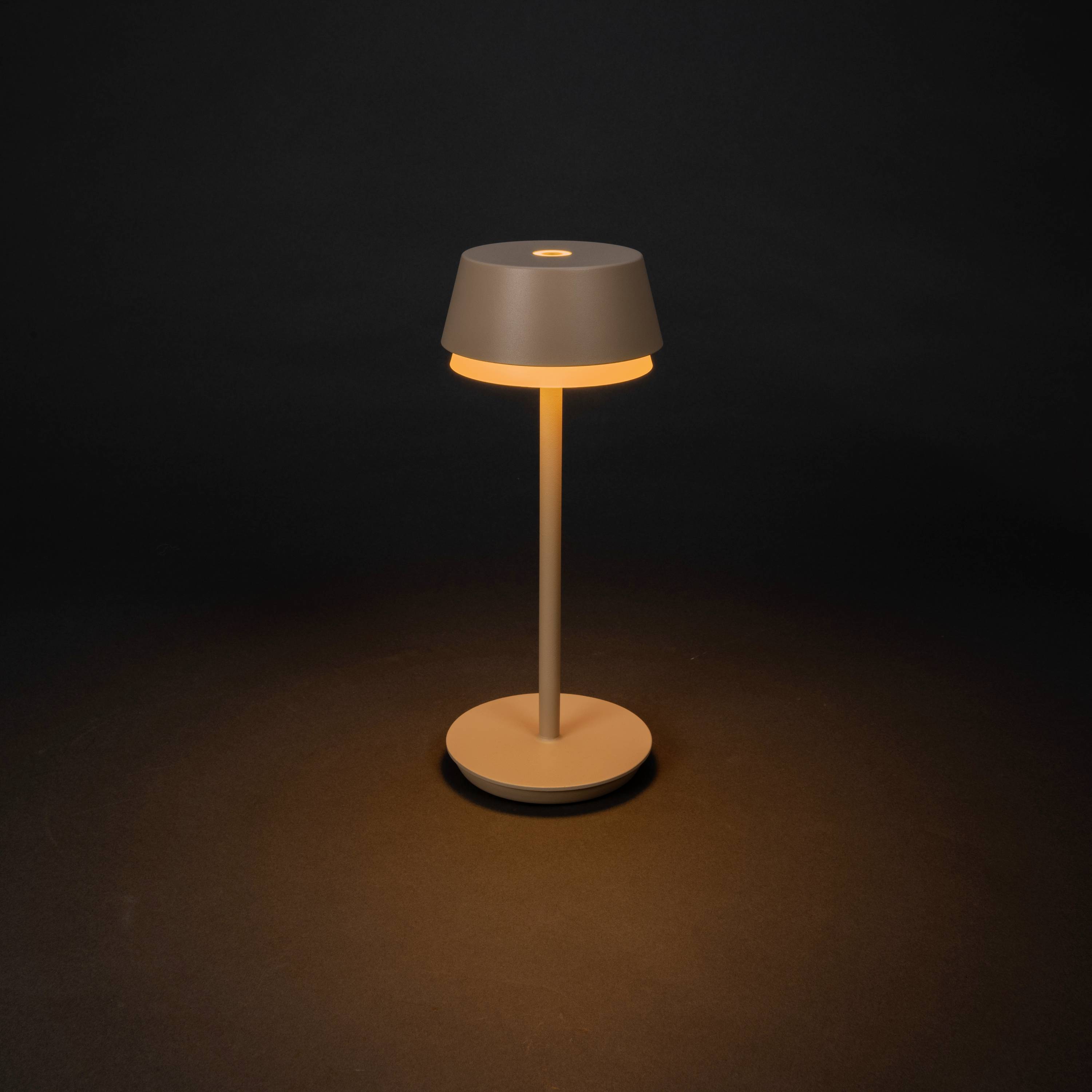 A modern table lamp with a simple, elegant design that radiates a warm light in a dark room.