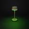 A brown table lamp with green light stands in front of a dark background.