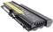 A black laptop battery with a yellow label and safety symbols is lying on a white surface.
