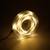 A coiled LED fairy light string emits warm, yellow light and lies on a dark background.