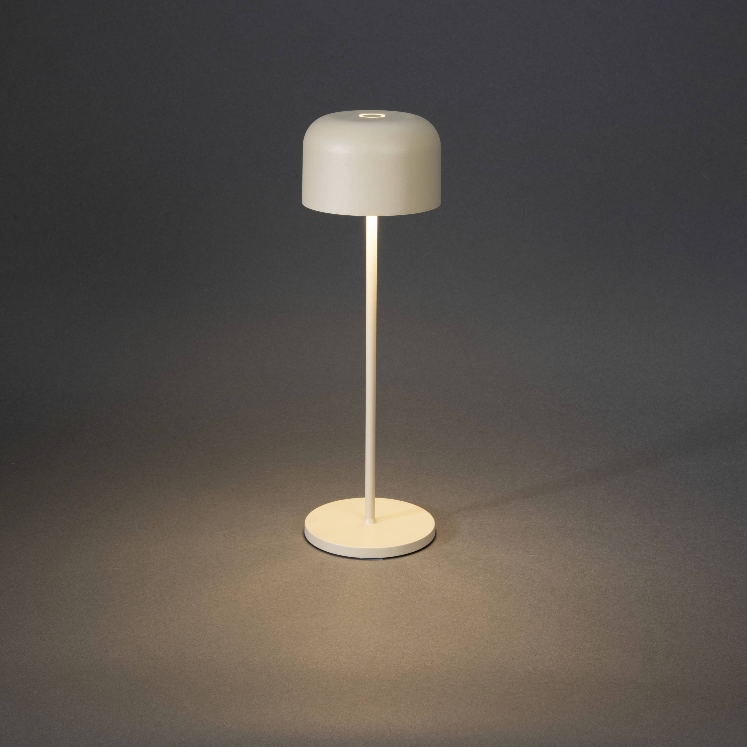 Minimalist table lamp with a round, flat shade. Emits warm light against a grey background, suitable for modern décor.