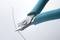A side cutter is cutting a thin wire. The handle of the pliers is blue.