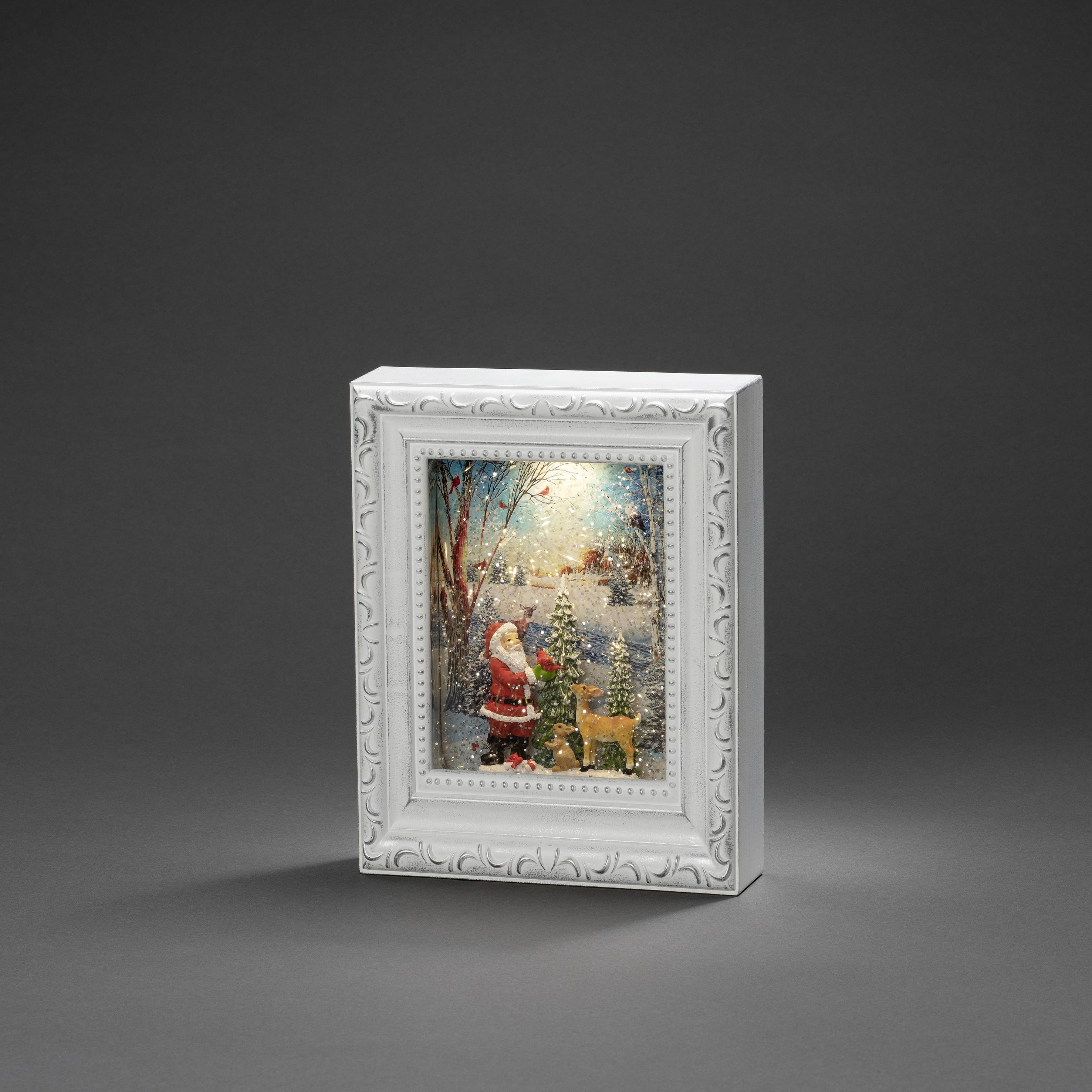 A lit image depicting Santa Claus and a reindeer at night in the snow, within a decorative white frame.