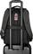 Travel rucksack made of sturdy fabric, suitcase's telescopic handle threaded through the loop, brand logo visible at the top.