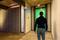A person approaches a front door with green light, while a motion sensor is activated and depicts waves.