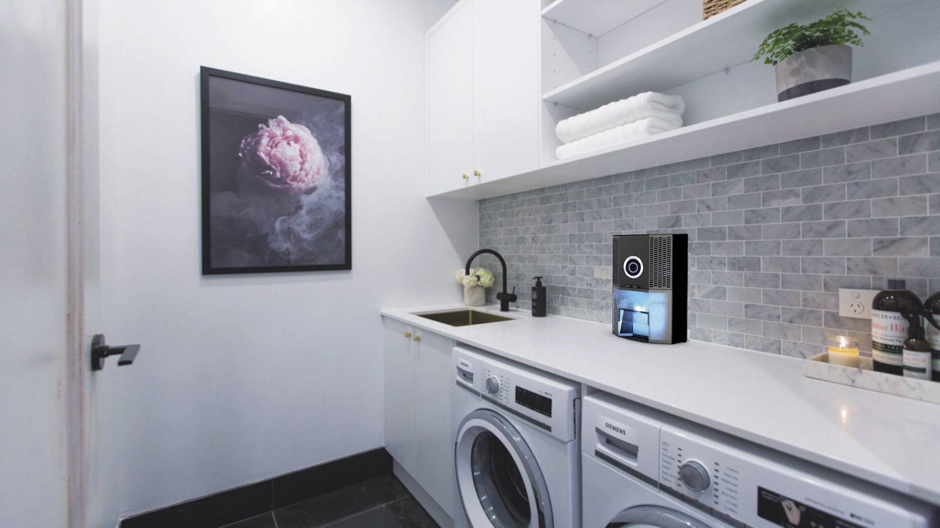 A utility room with a washing machine and tumble dryer beneath a worktop. A picture of a pink flower hangs on the wall.