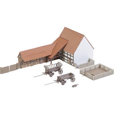 Miniature model of a half-timbered farmhouse with a red roof, two wooden carts and fences, set against a white background.
