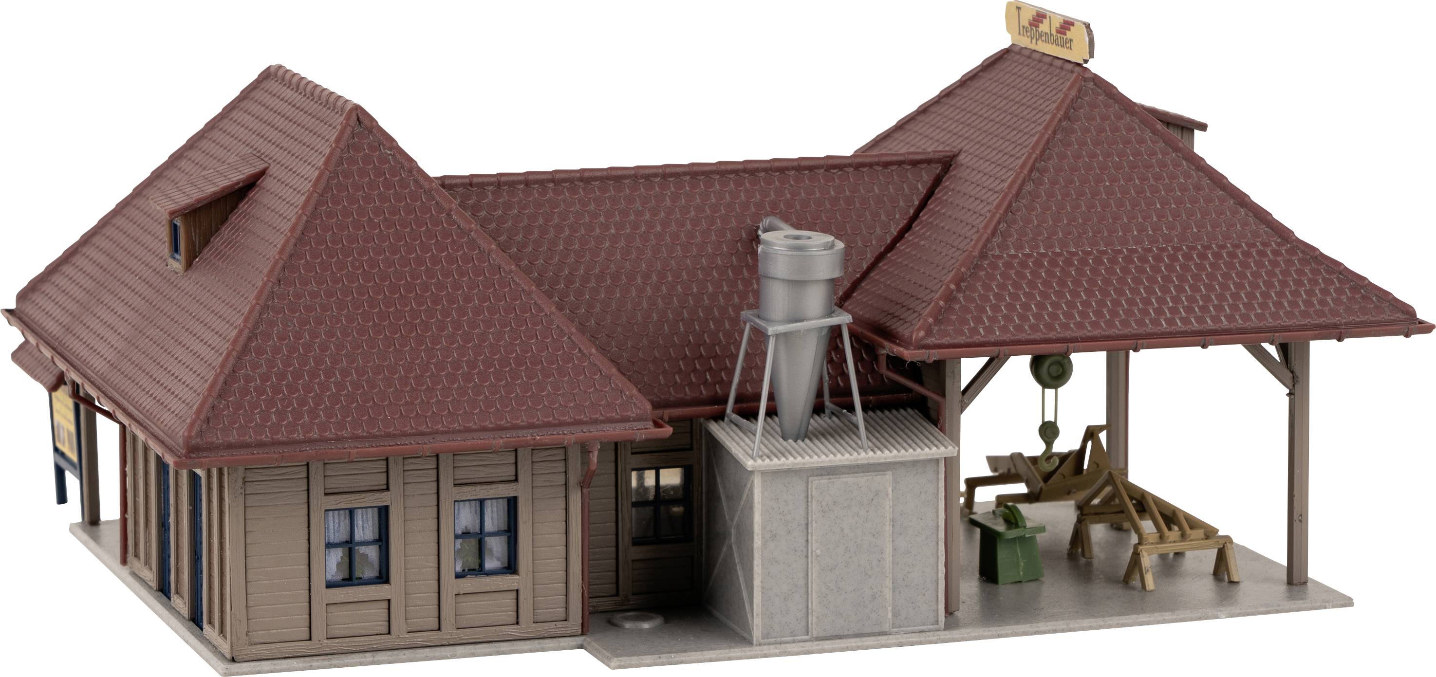 Model of a small railway station with red roofs and a wooden veranda. Decorative elements such as a fence and an advertising board are visible.