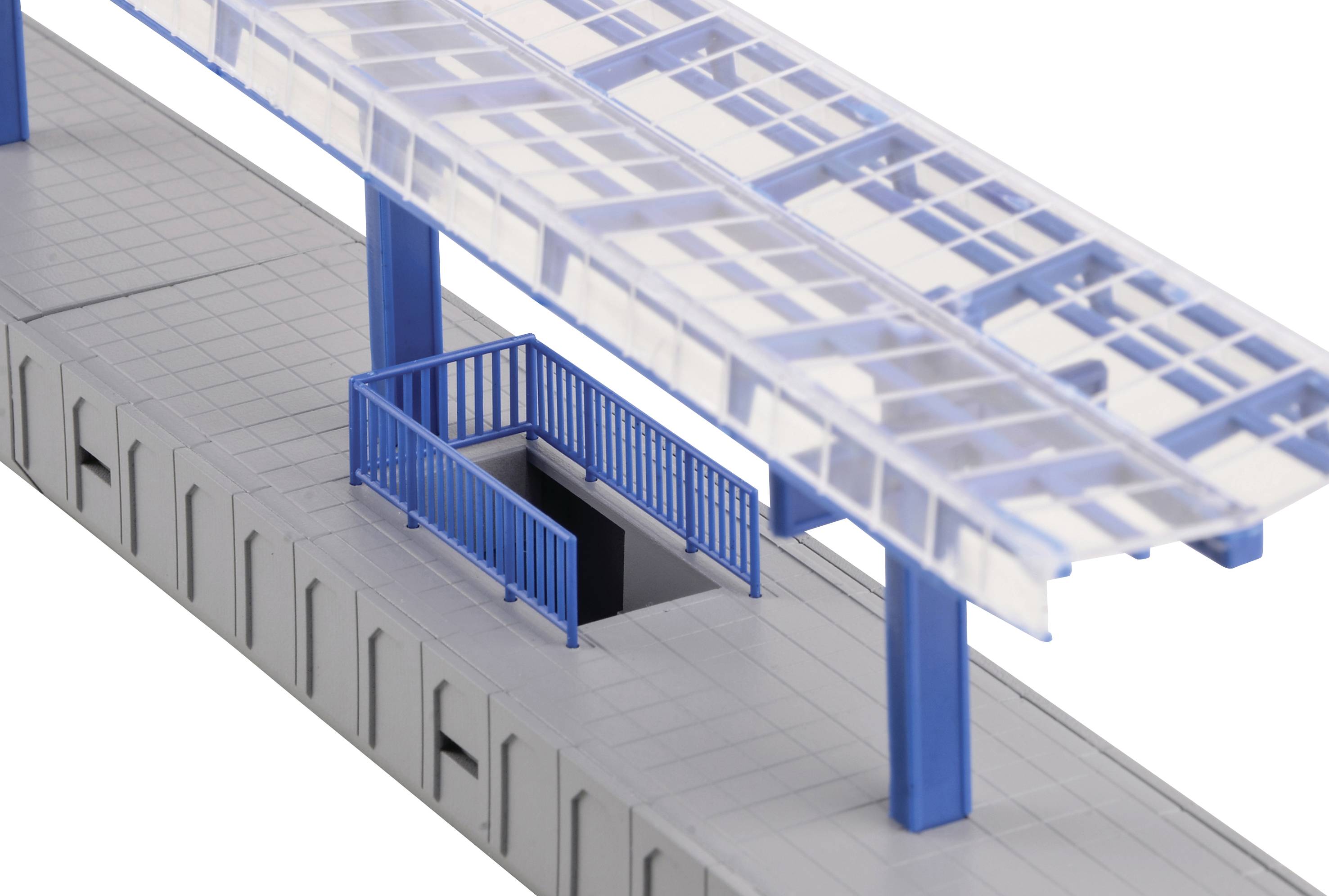 A miniature model railway platform with blue columns and canopy, featuring a staircase leading to an underground area.