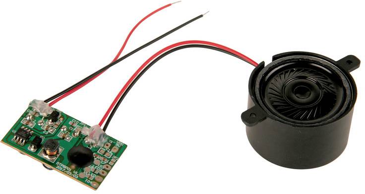 A small green electronic circuit board with various components, connected to a round black speaker via two wires.