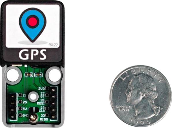 'Small GPS module next to a US 25-cent coin for size comparison. The chip displays a symbol with a red dot in a blue location symbol.'
