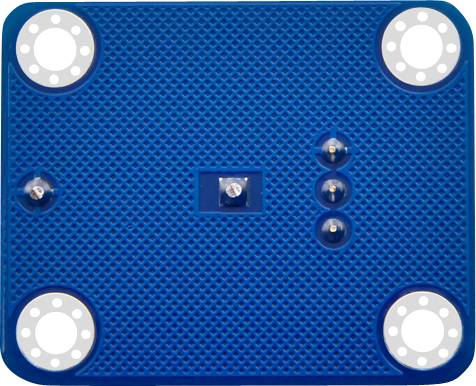 Blue rectangular object with four light rings at the corners and several protrusions in the centre, placed on a textured surface.
