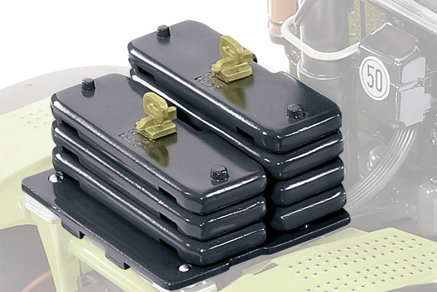 Stack of black metal weights on a piece of agricultural machinery, used for balancing weight. A motor block is visible in the background.