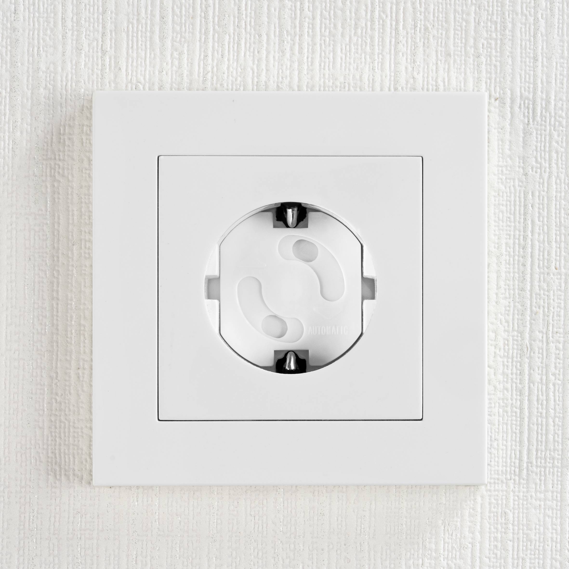 A white wall socket in close-up, with child safety features, built into a textured wall.