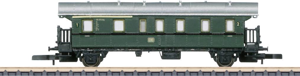 Old green railway passenger carriages on tracks, side view, with multiple windows and historical details.