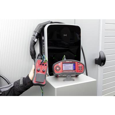 A charging device for electric vehicles is being tested with a testing instrument. A hand is holding the testing instrument, which displays results.