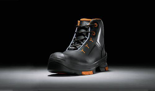 A black safety shoe with orange accents and a robust design, presented on an illuminated, dark background.