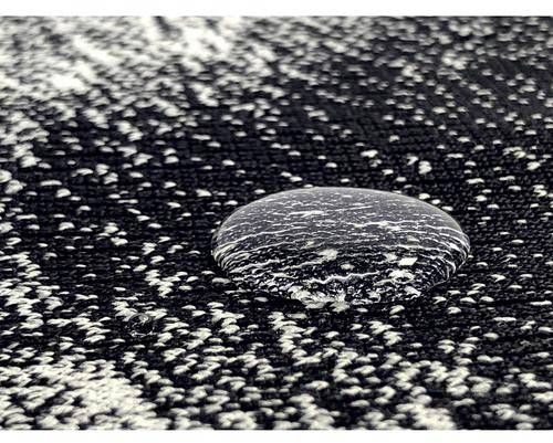 Water-repellent droplet on textured, black fabric. The fabric reveals a pattern emphasised by the water bead.
