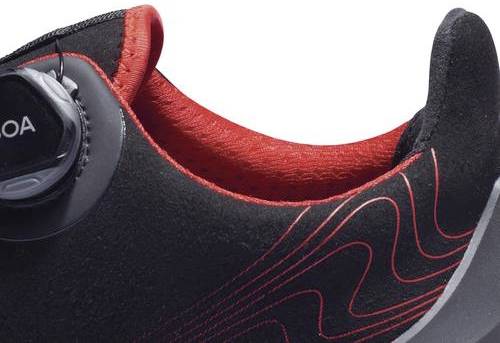 Black sports shoe with red inner lining and red lines. Side closure system. Shoes for running or sporting activities.