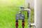 A digital irrigation timer is attached to an outdoor tap. The timer displays '05:00'. Grass can be seen in the background.