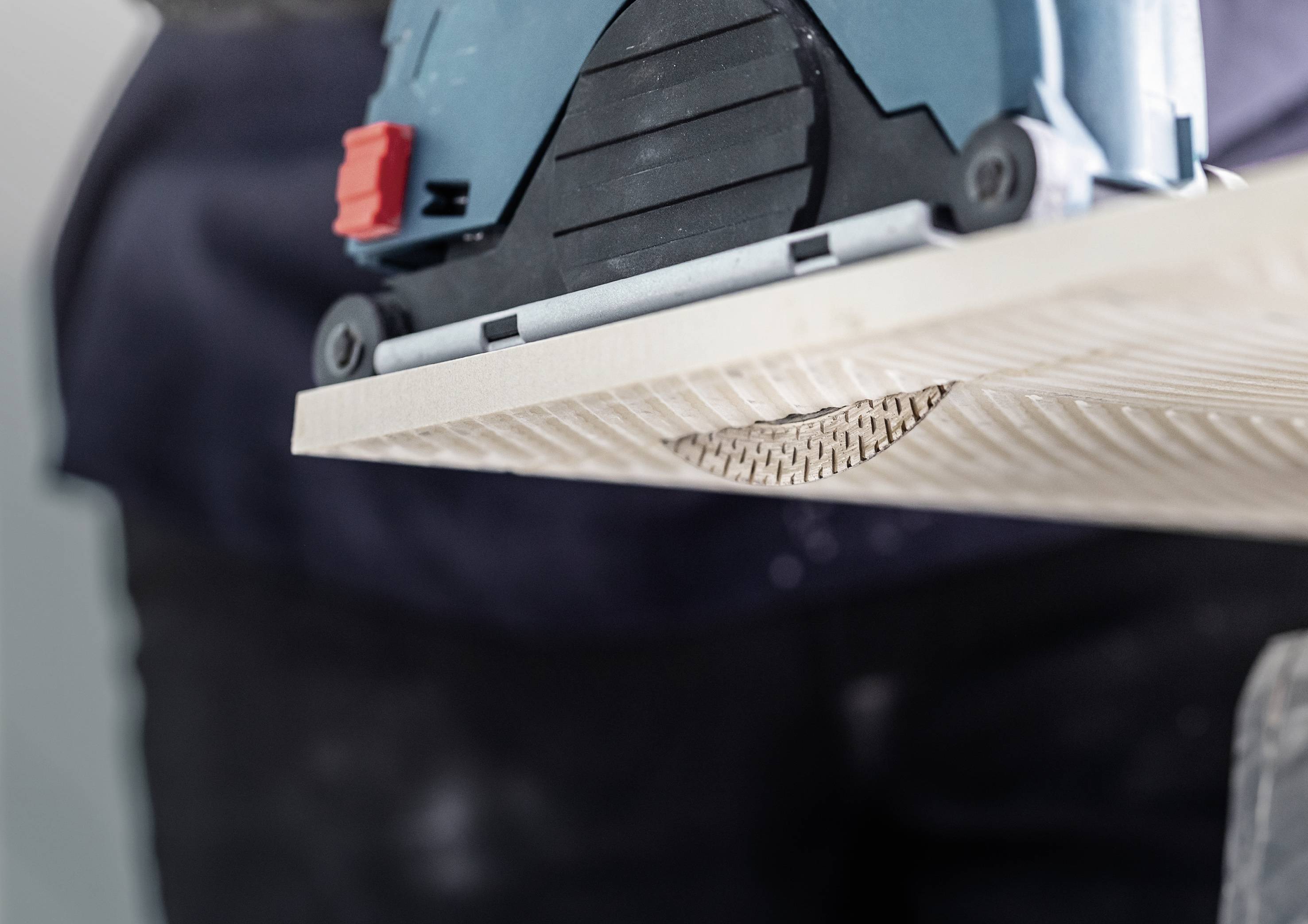 Electric sander grinding a wooden board. Close-up of the sanding process with visible wood shavings.