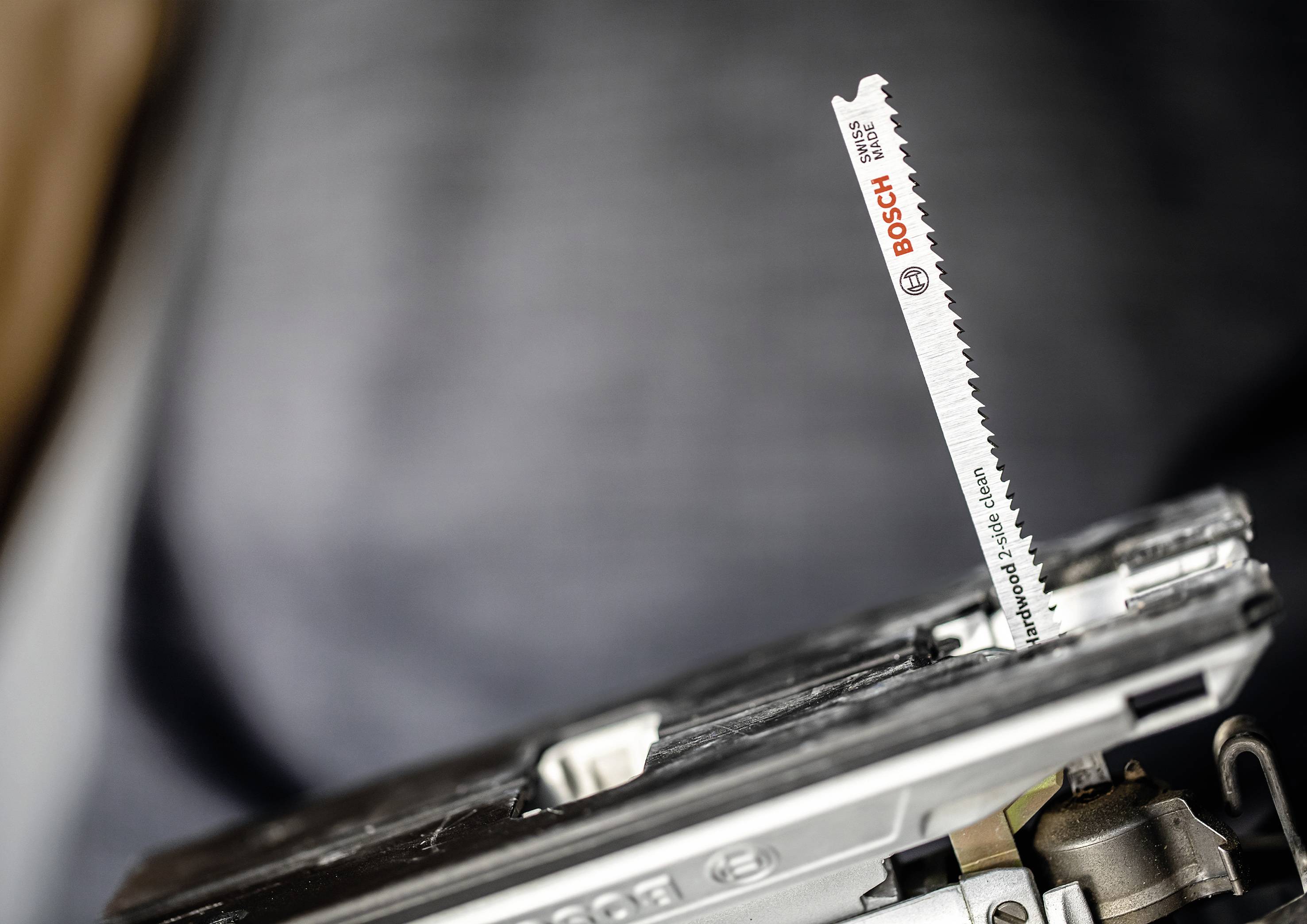 A jigsaw with a Bosch saw blade inserted, focusing on the saw blade with visible teeth, ready to cut.