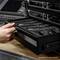 A hand pulls out a drawer from an audio device, containing several microphone units.