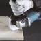 A worker wearing white gloves is cutting a marble slab with an angle grinder.