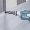 A person is using a cordless drill to screw a screw into a metal plate. The drill is blue and is a Makita brand.