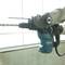 A person is operating a drill hammer in a workshop, ready to drill a hole in a concrete wall.