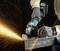 Tool in Action: A worker wearing safety gloves is cutting metal with an angle grinder, sparks flying.