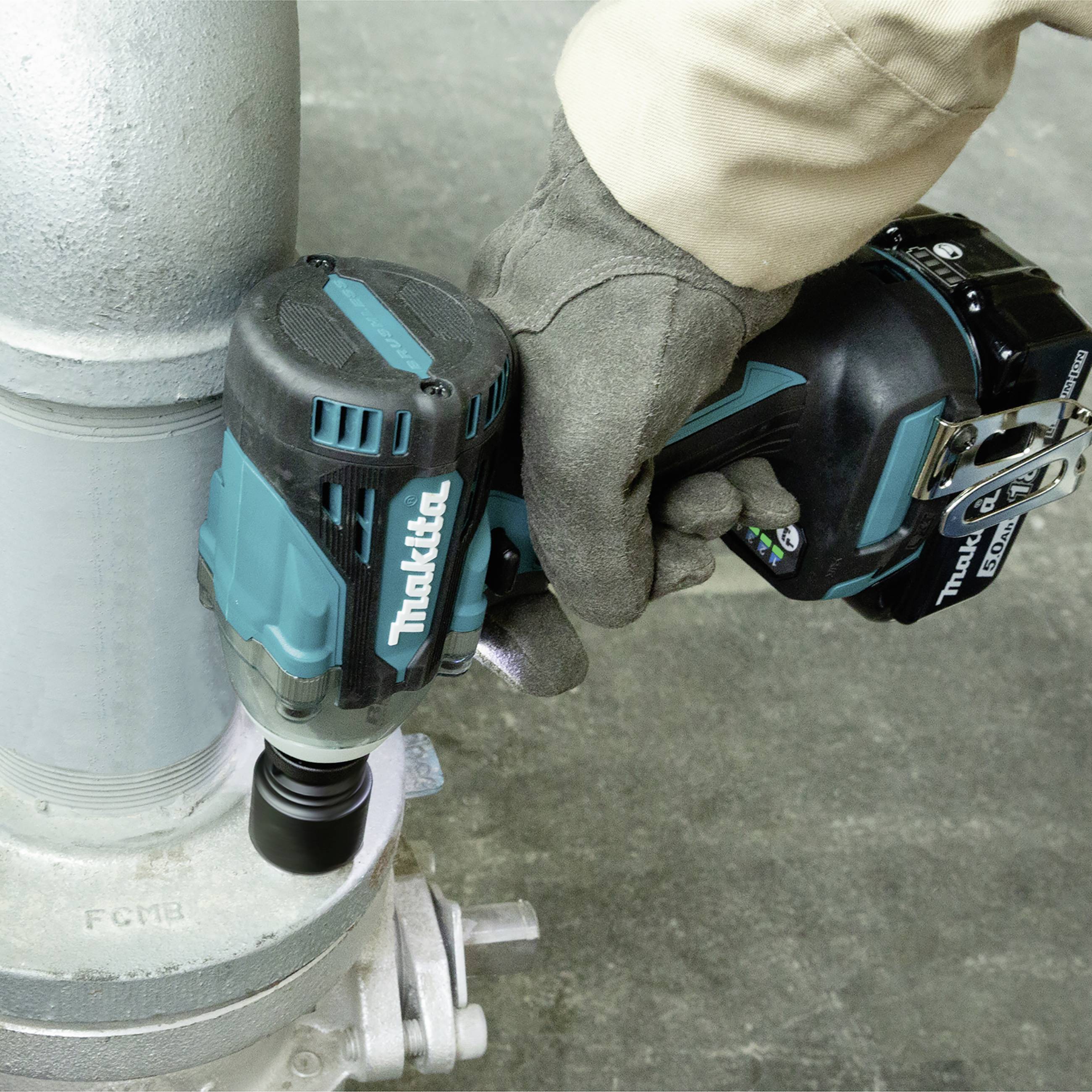 A person is using a cordless drill to tighten a nut on a pipe connection.