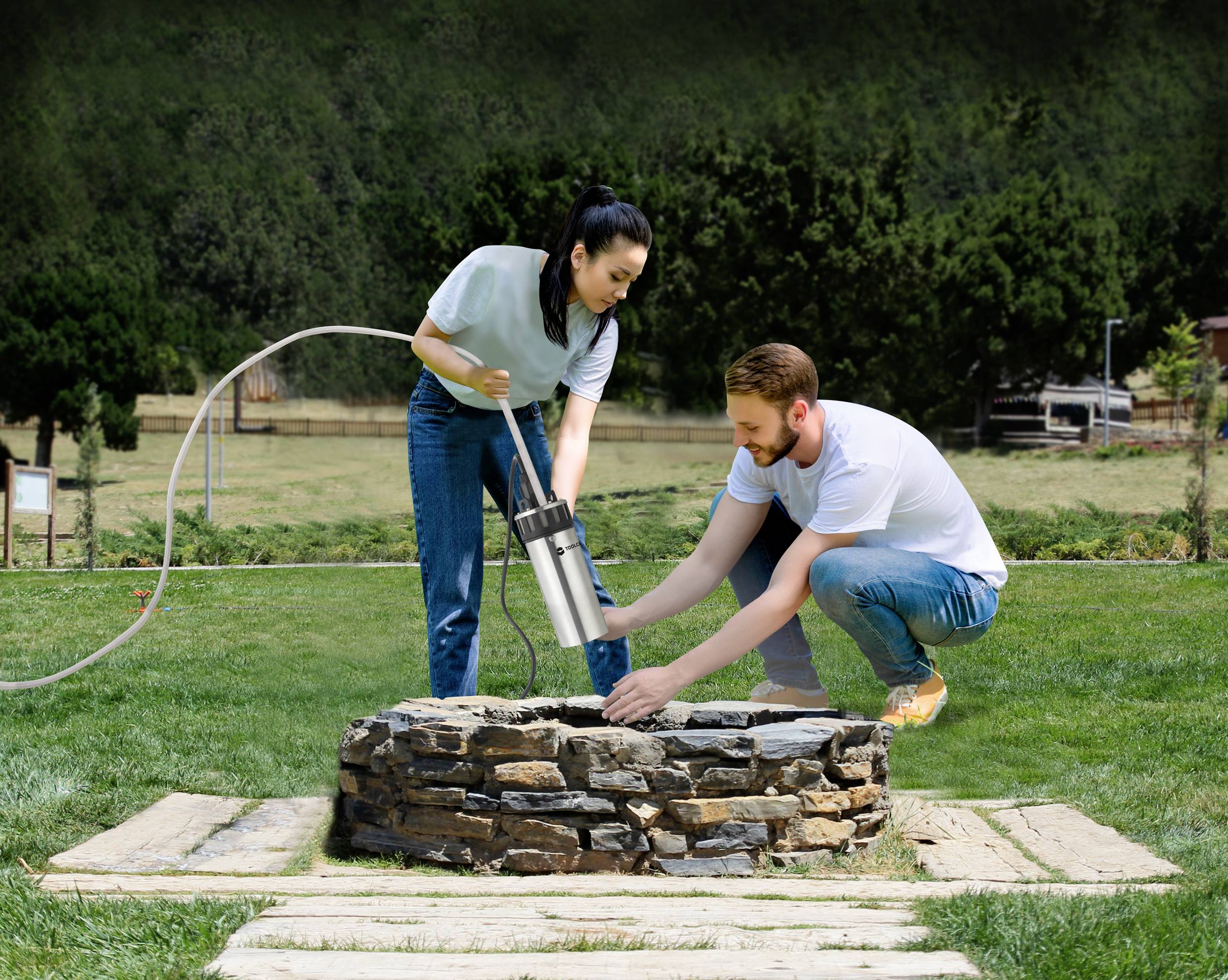 A woman and a man are jointly installing a water pump in a brick well within a park-like garden.