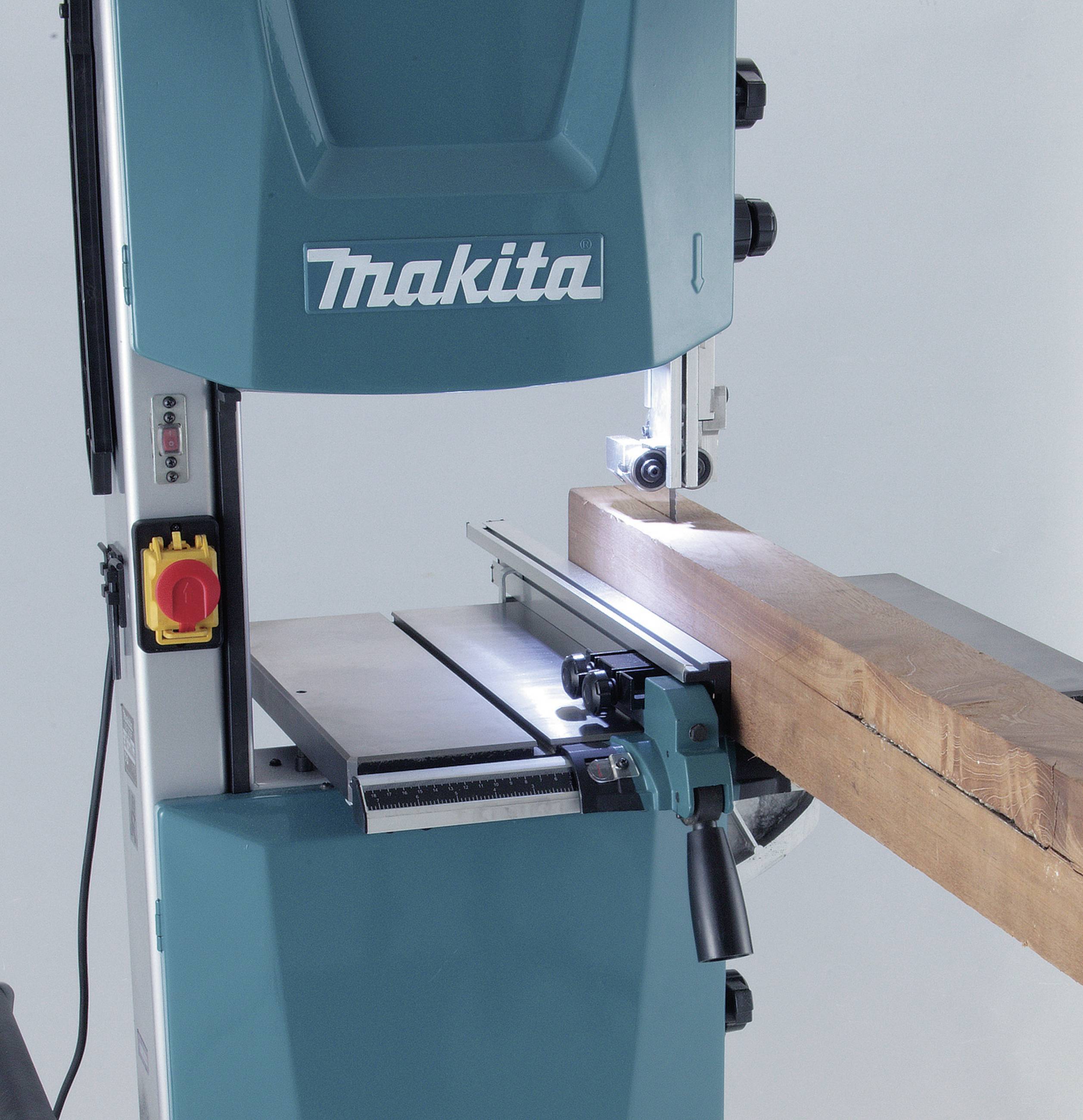 A blue band saw is cutting through a wooden beam. There is a safety guard and an emergency stop button on the machine.