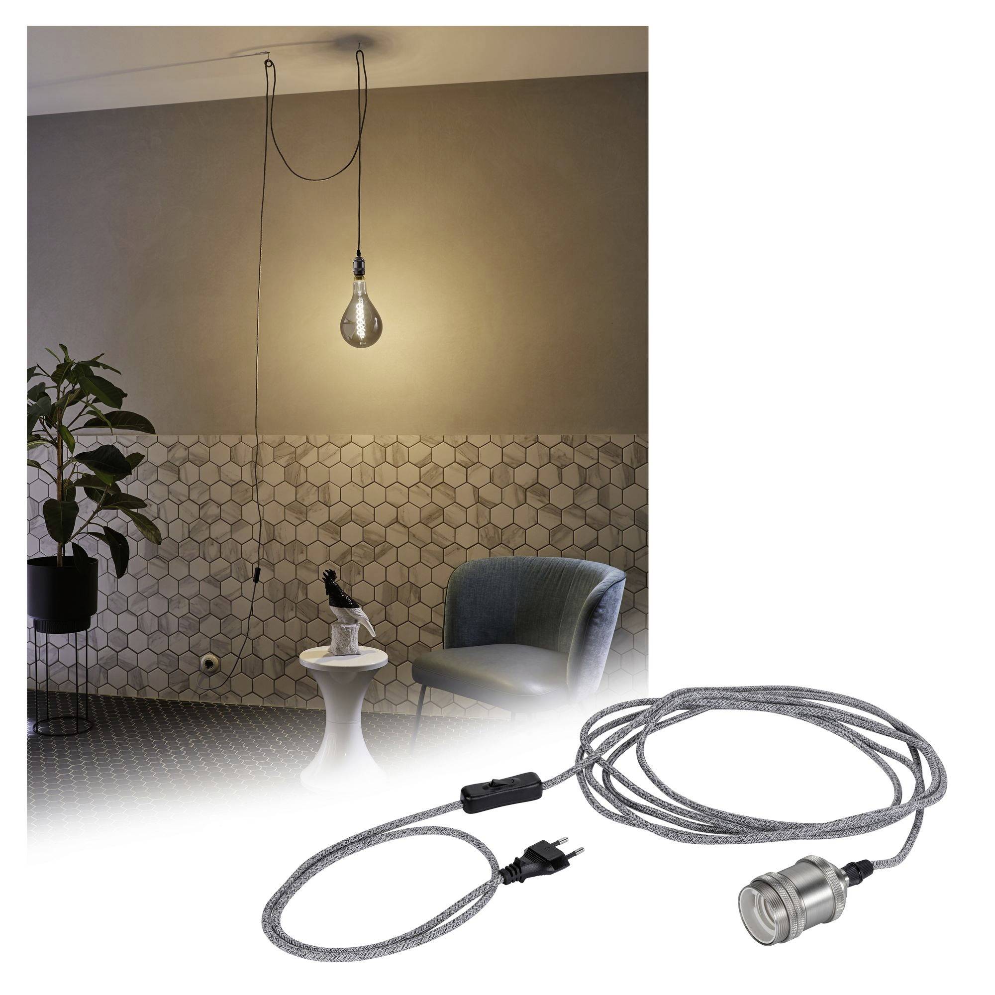 Pendant light with textile-covered cable, hanging from the ceiling above a table with decorative items in a modern interior.