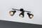 A three-armed black ceiling light with adjustable spotlights mounted on a room ceiling, illuminating in different directions.