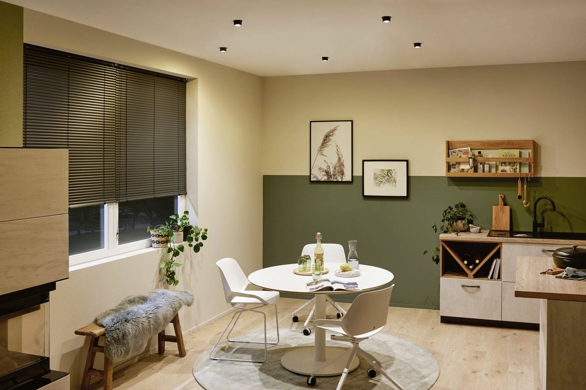 Cosy kitchen with a dining table, four chairs and plants. Pictures are hung on the wall. Modern interior in a Scandinavian style.