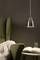 A green armchair with a white throw, next to a small side table with an open book and a glass of water, illuminated by a pendant light.