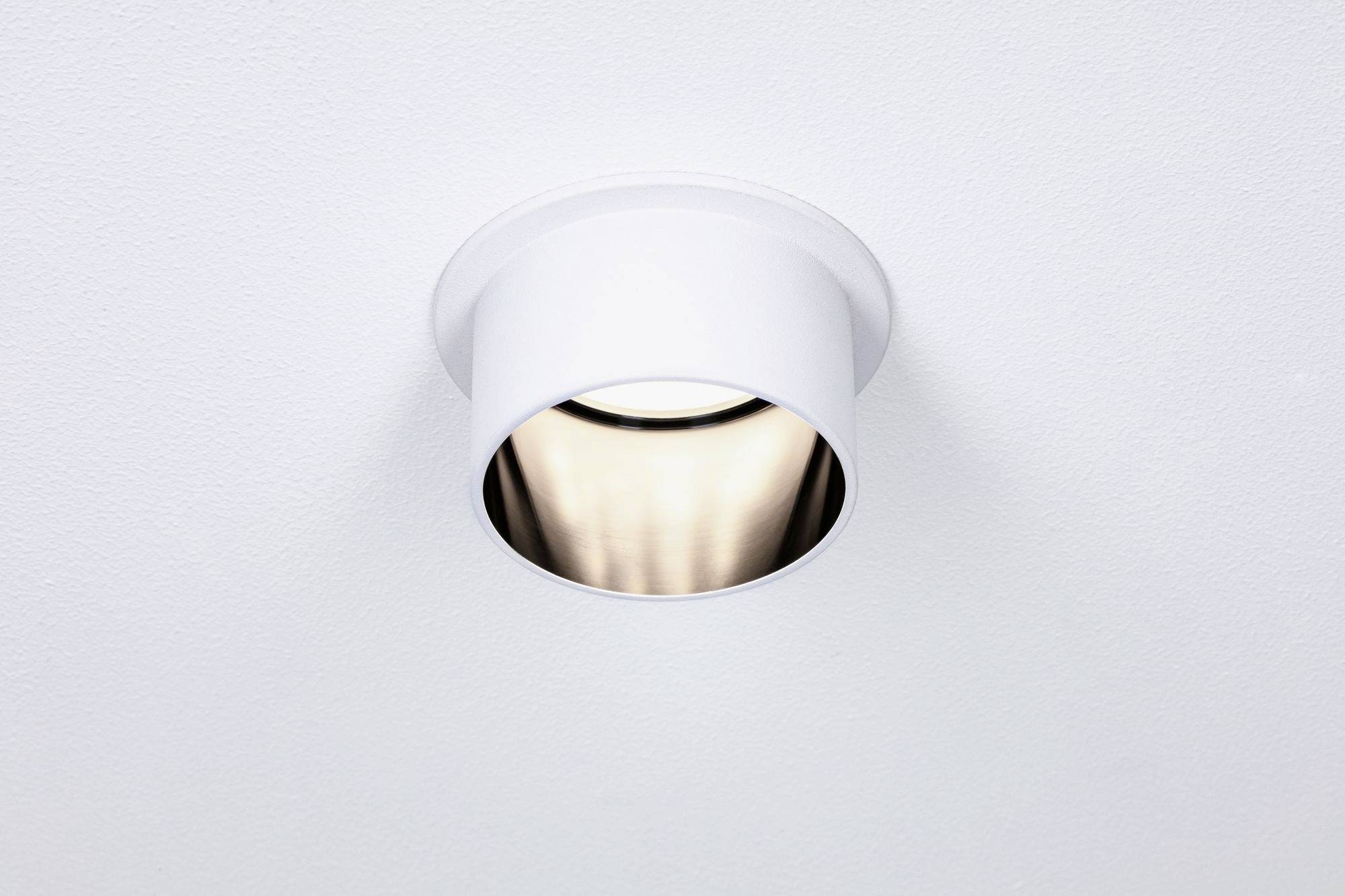 A white ceiling light with a built-in, luminous spotlight radiates warm light downwards.